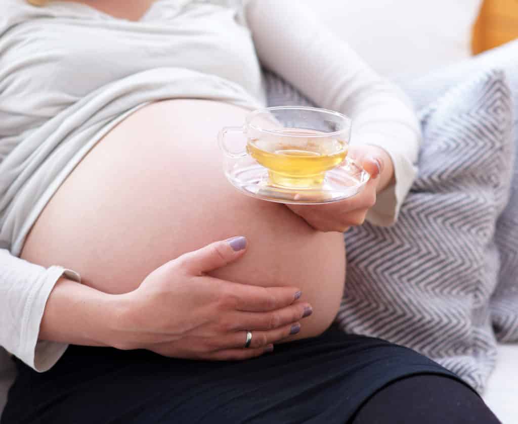 pregnant woman holding a green tea cup