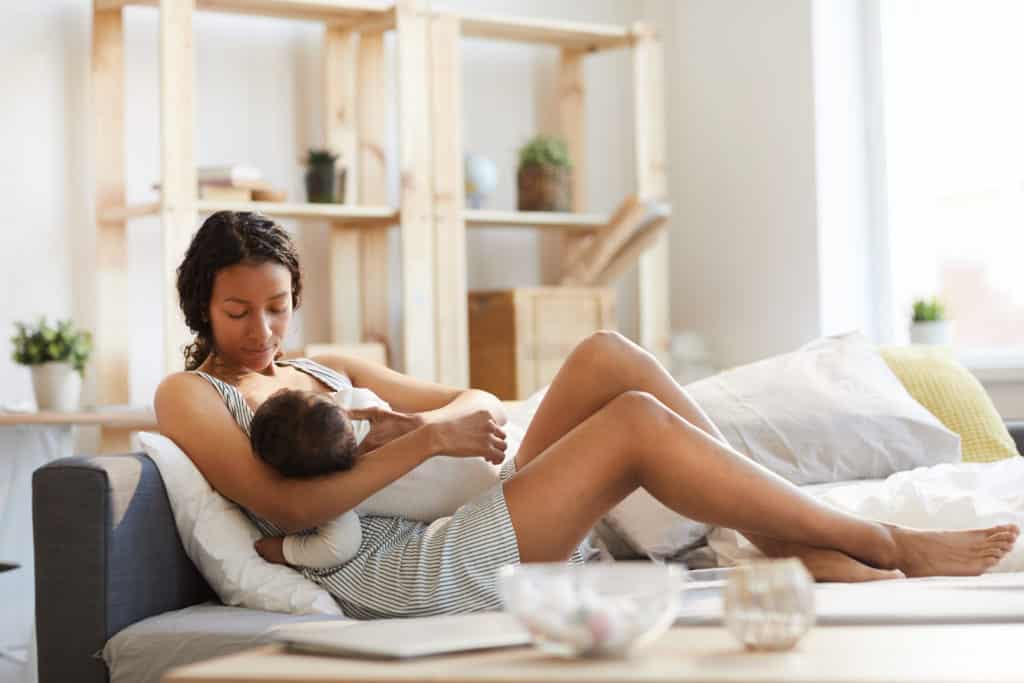 mum breast feeding child on a couch