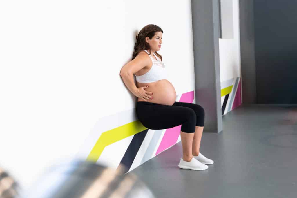 pregnant woman doing standing pelvic tilt abs exercise